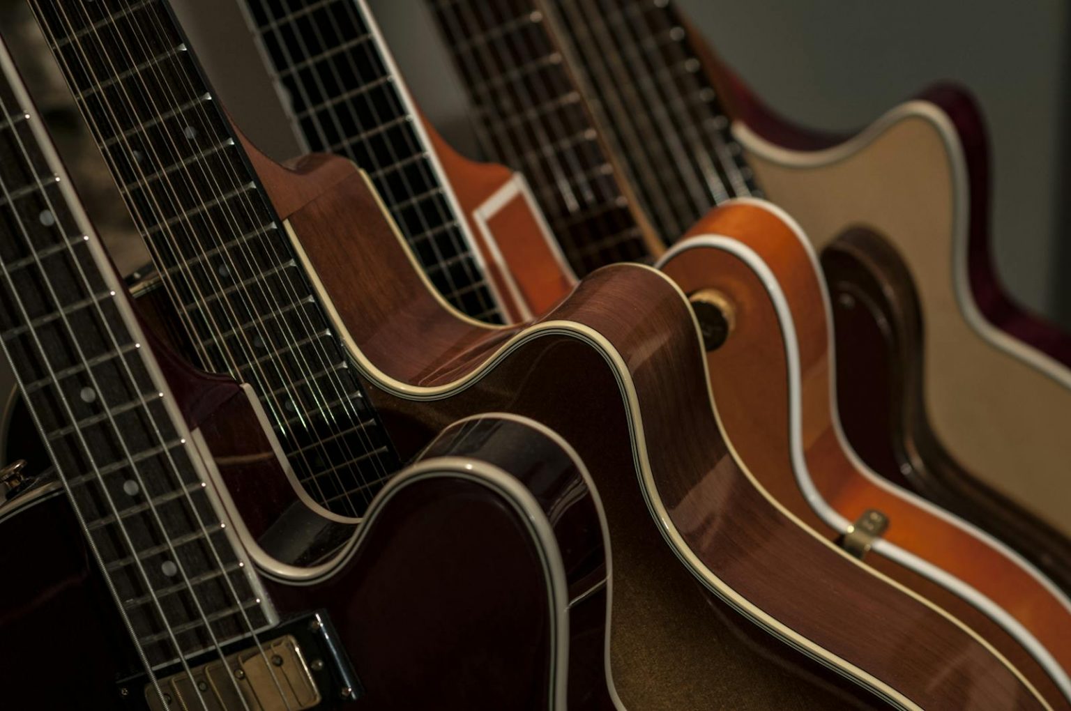 Detailed shot of diverse acoustic guitars lined up, showcasing strings and wood texture.